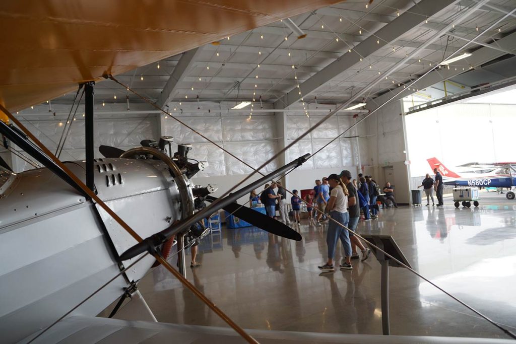 The crowd mills about, framed by a plane's wings.